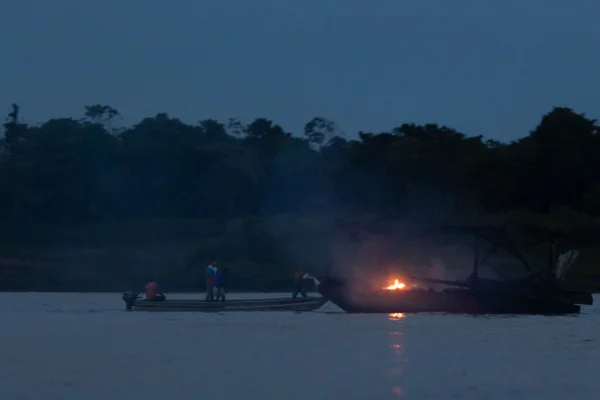 garimpeiro tenta apagar fogo em balsa no Rio Madeira, no Amazonas