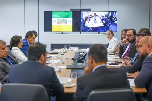 A presidente do PT, Gleisi Hoffmann, participando de reunião com lideranças de partidos aliados. Ela aparece debruçada sobre mesa, observando alguém falar. Reunião é no Gabinete de Transição - Metrópoles