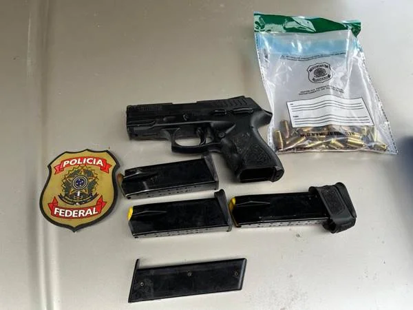 Arma, cartuchos e projéteis aparecem espalhados em mesa ao lado de distintivo da Polícia Federal após serem apreendidos com bolsonarista suspeito de ataque à PF - Metrópoles