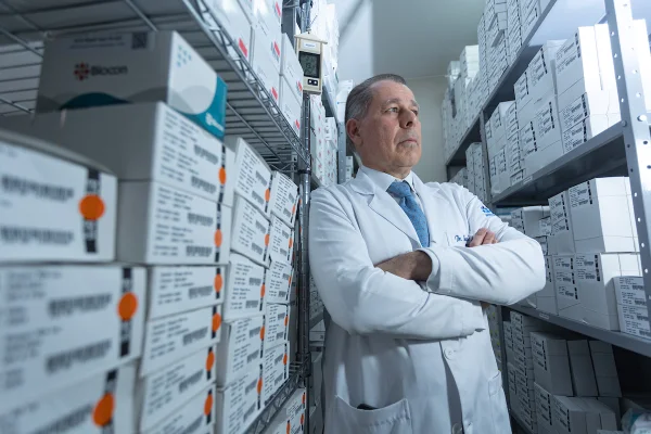 Foto colorida de um médico no meio de estantes com remédios para tratamento do Lúpus - Metrópoles