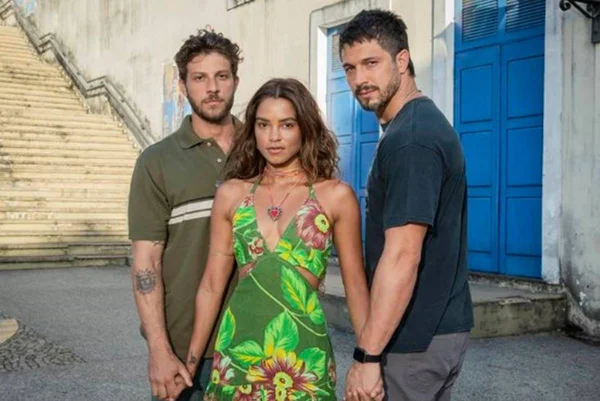 Foto colorida de Lucy Alves, Rômulo Estrela e Chay Suede dando as mãos para a novela Travessia - Metrópoles