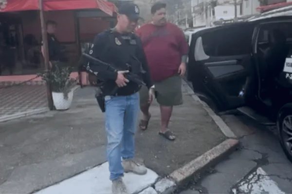 Imagem colorida do suspeito de envolvimento na morte do ex-delegado geral da Polícia Civil paulista sendo preso - Metrópoles