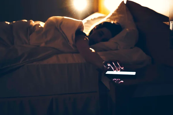 Pessoa deitada na cama tocando no telefone - Metrópoles