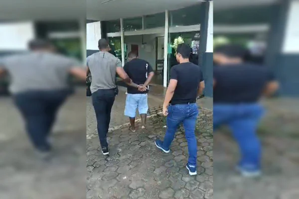 Foto colorida de homem sendo levado à delegacia