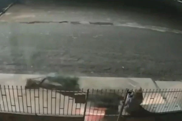 Imagem colorida de câmera de segurança mostra uma moto sem condutor antes de atingir mulher idosa que estava sentada em banco na frente de sua casa - Metrópoles