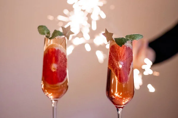 Duas taças com drinques e fogos no fundo