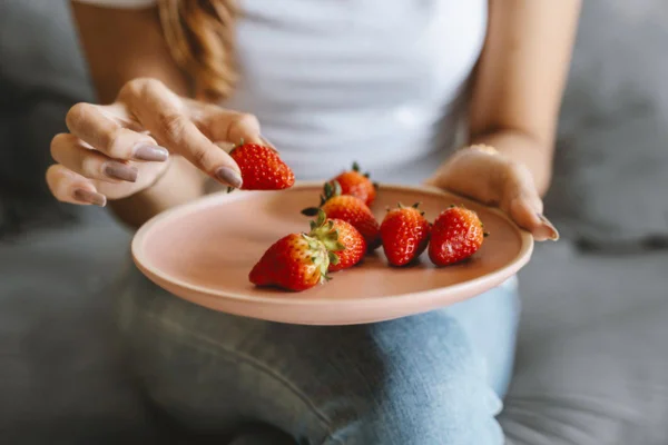 Imagem colorida de mulher comendo morango