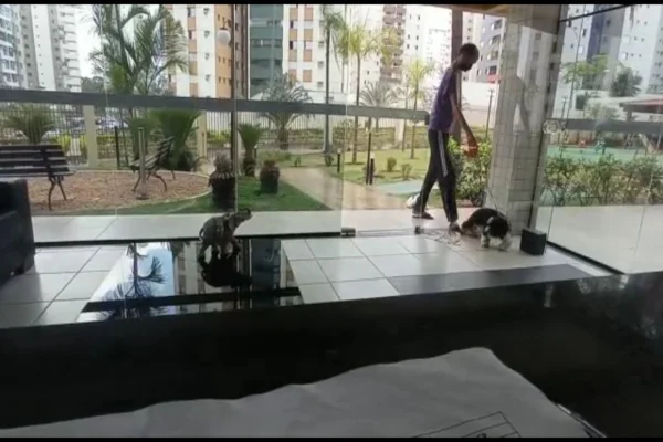 Homem em portaria de prédio com dois cachorros na coleira