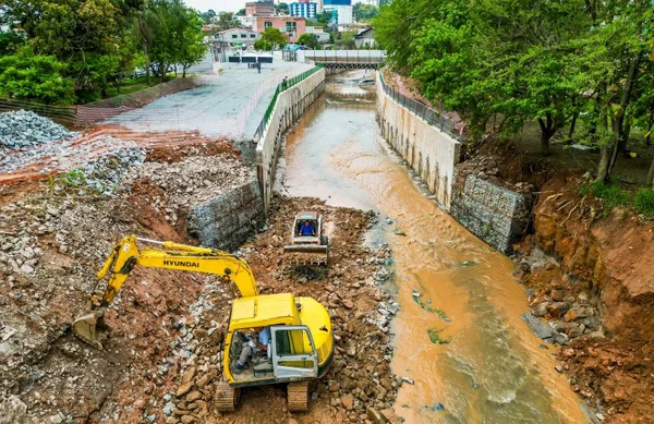 Foto colorida de retroescavadeira em obras de contenção de margens de rio da prefeitura de são paulo - metrópoles