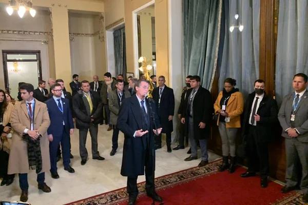 Presidente Bolsonaro fala em coletiva de imprensa, em Moscou, sobre o desastre em Petrópolis. Ele está cercado de ouvintes e jornalistas e usa sobretudo, com um microfone na frente - Metrópoles