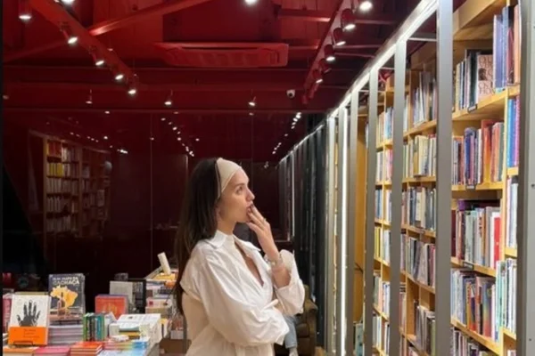 Atriz Rafa Kalimann parada em frente à estante de livros - Metrópoles