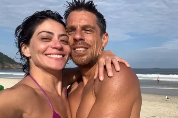 Carol Castro e Leandro Dias posam juntos e sorridentes na praia - Metrópoles