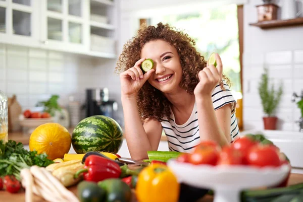 Foto colorida de mulher segurando pepino em frente aos olhos - Metrópoles
