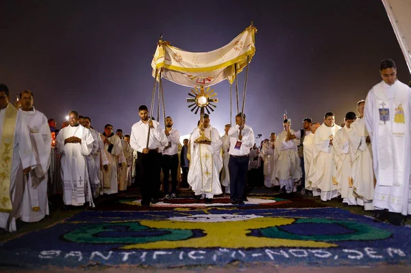 Peregrinação na Esplanada em comemoração ao Corpus Christi. Sob um tapete estampado, religiosos de batina passam segurando símbolos religiosos - Metrópoles