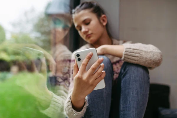 Imagem colorida de menina mexendo no celular - Metrópoles