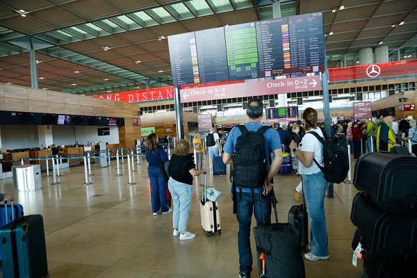 Imagem colorida de pessoas paradas olhando telas. Aeroporto, voos
