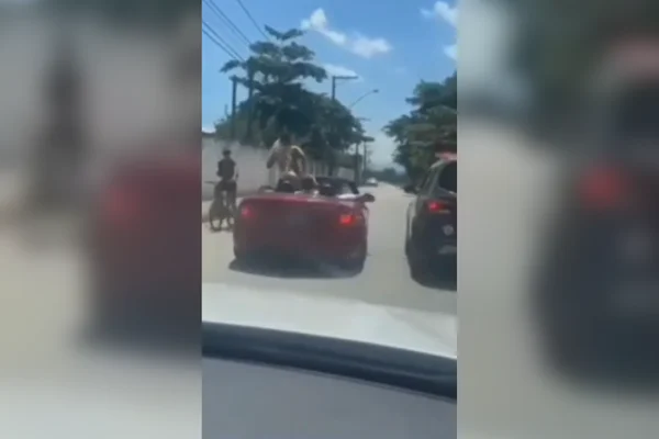 Imagem colorida de uma mulher somente de roupa íntima sensualizando em cima de um carro conversível vermelho - Metrópoles