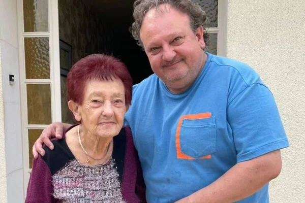 foto colorida do chef erick jacquin de camiseta azul ao lado de senhora dos cabelos marsala vestindo blusa estampada e blusa de frio vinho - metrópoles