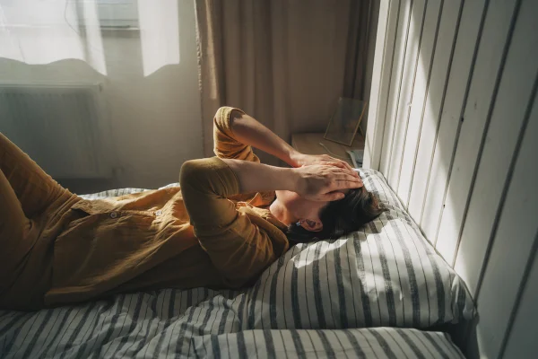 Mulher deprimida ou sentndo dor deitada na cama. Metrópoles