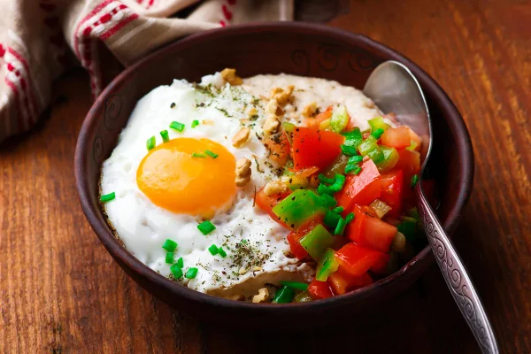 Foto colorida de ovo frito em frigideira acompanhado de tomate, pimentão cheiro-verde - Metrópoles