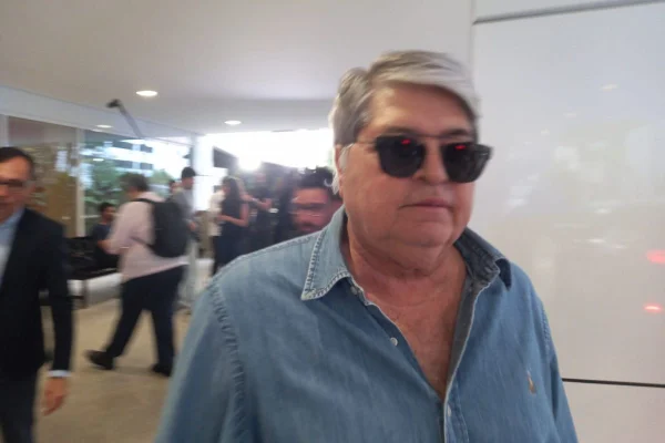Imagem colorida mostra homem grisalho, com sobrepeso. Ele veste camisa jeans e óculos escuros - Metrópoles