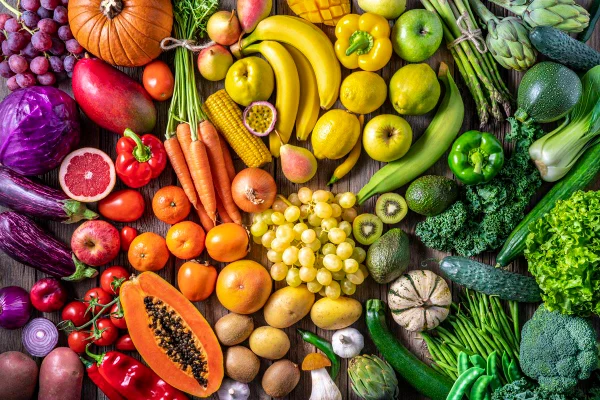 Foto colorida - frutas e legumes de diversas cores enfileirados para formar um arco-íris