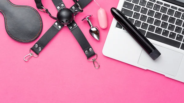 Vários vibradores dispostos em cima de um computador, com um fundo rosa - Metrópoles
