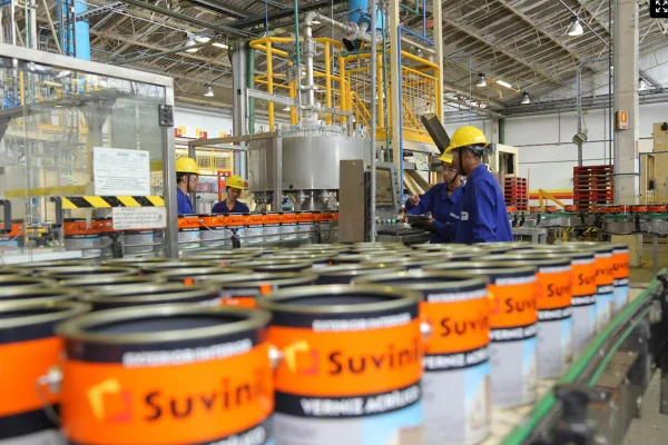 Imagem de fábrica da Suvinil, com funcionários trabalhando e latas de tinta - Metrópoles