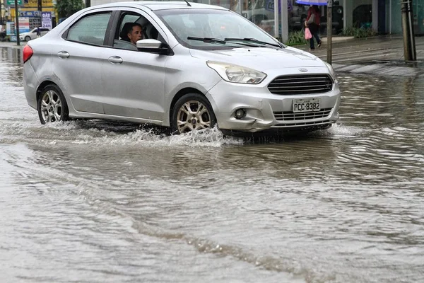 Imagem colorida de carro atravessando rua alagada em Pernambuco - Metrópoles