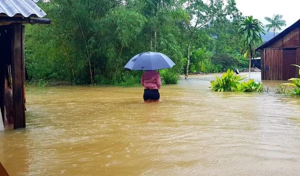 Mulher caminha em aldeia indígena alagada no litoral de São Paulo