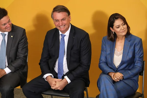 O presidente Jair Bolsonaro sorri ao lado da primeira-dama, Michelle Bolsonaro, e do ministro da Cidadania, João Roma