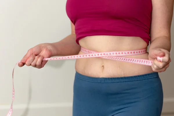 Foto colorida de mulher com fita métrica na região abdominal - Emagrecimento: entenda se é possível perder peso rápido sem remédio - Metrópoles