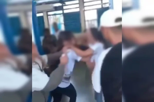 Meninas brigando e menino de boné branco de costas, olhando a briga