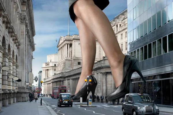 Foto colorida de pés gigantes femininos de salto alto pisando em uma cidade pequena - Metrópoles