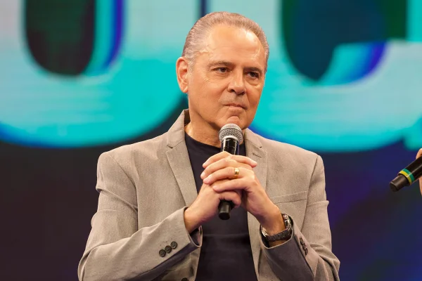 Imagem colorida de Luis Roberto sentado falando em um microfone - Metrópoles