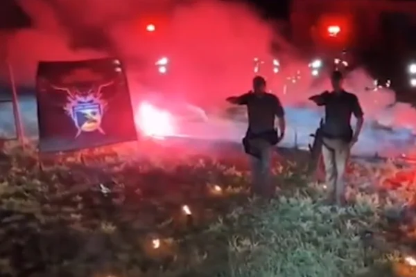 Imagem colorida de PMs em ritual com tom supremacista e cruz queimada