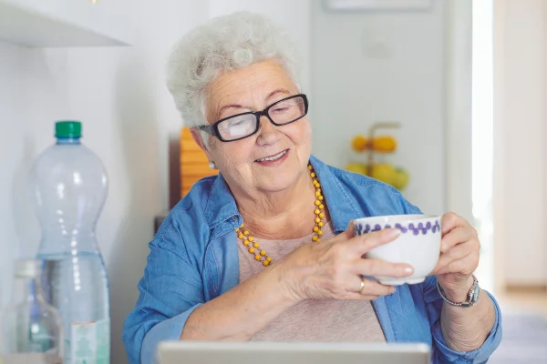 Foto colorida de mulher com blusa azul erguendo uma xícara branca - Metrópoles
