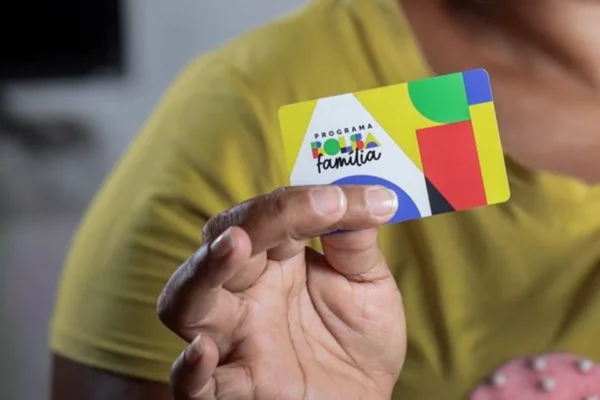 Imagem colorida de pessoa com o cartão do Bolsa Família - Metrópoles