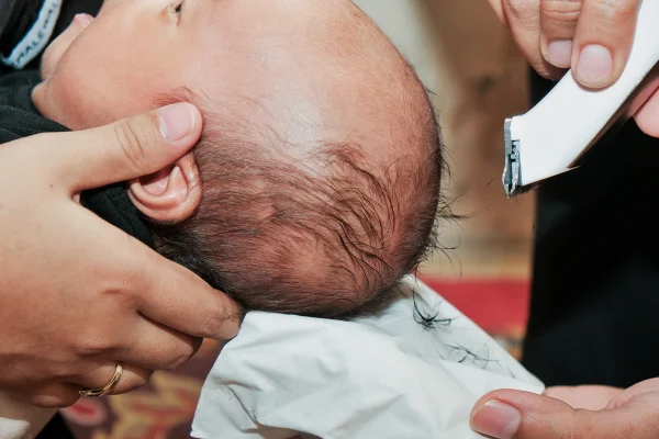 Foto colorida de bebê tendo a cebça raspada