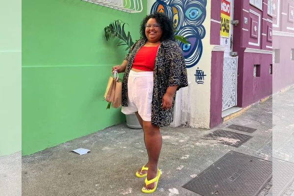Mulher em pé sorrindo em rua - Metrópoles