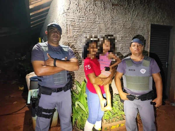 Imagem colorida mostra policiais militares (PM) com uma mulher e uma criança entre eles; a menina foi resgatada no meio da mata após sair correndo em uma distração da avó