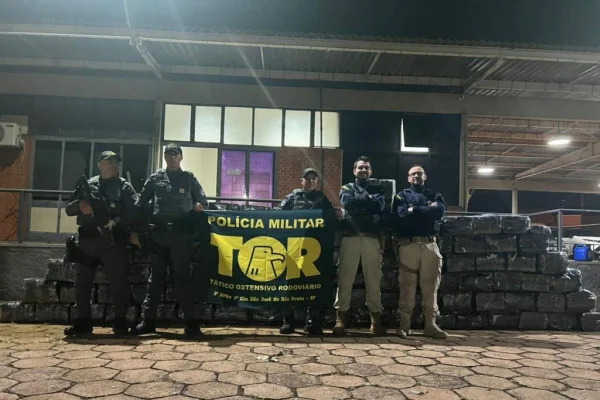 Imagem colorida mostra policiais ao lado de maconha encontrada em carga de macarrão - Metrópoles