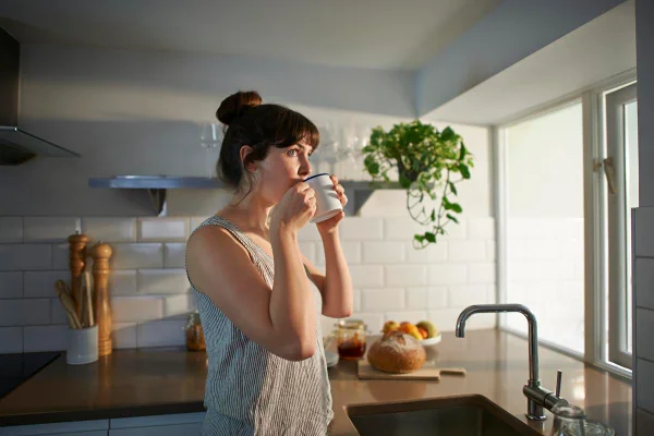 Foto colorida de uma mulher tomando café - Metrópoles