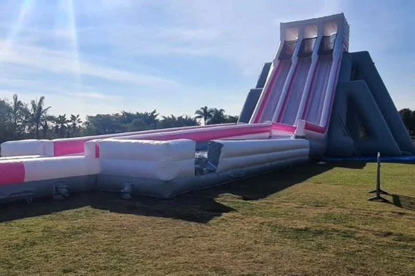 Imagem colorida de tobofã inflável. Brinquedo tem três pistas, pintadas de rosa e de branco - Metrópoles