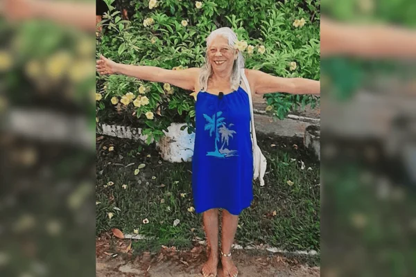 Imagem colorida de uma mulher de cabelos brancos em frente a um jardim - Metrópoles
