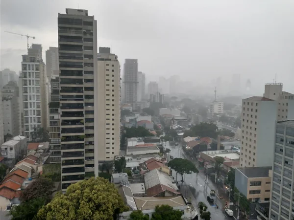 Imagem mostra prédios e rua em meio à chuva - Metrópoles