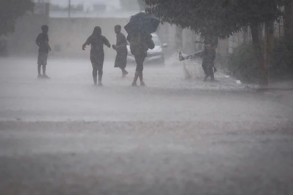 Meninos brincando na chuva no Sol Nascente
