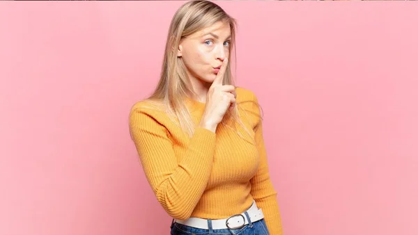 Mulher com dedo na boca, em gesto de silêncio