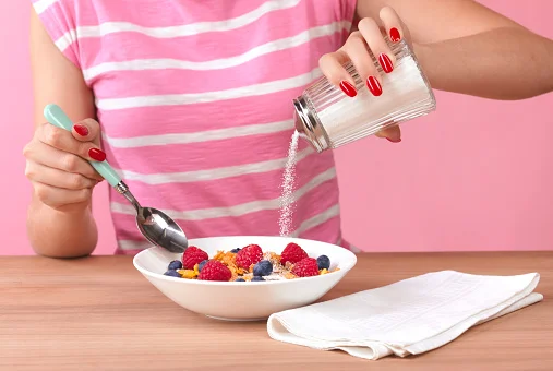 mulher comendo taça de frutas e colocando açúcar