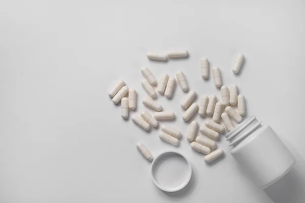 Pílulas ou medicamentos espalhados sobre um fundo branco - Nutricionista explica os benefícios do suplemento NAC para o fígado - Metrópoles